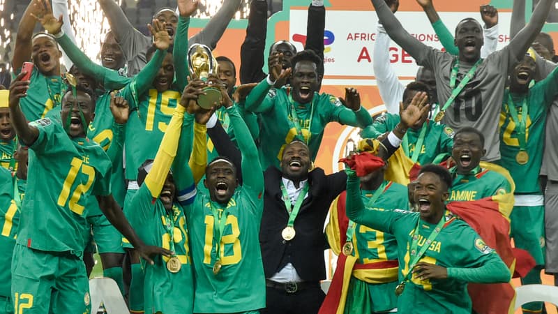 Image de Sport. ​L’Algérie et le Sénégal s’affrontaient samedi en finale du championnat d’Afrique des nations. Ce sont les Lions de la Téranga qui l'ont emporté à l'issue des tirs au but. Après avoir remporté la Coupe d’Afrique des nations l’année dernière au Cameroun, le Sénégal a remporté le CHAN samedi. Le championnat d’Afrique des nations est une compétition africaine dont les sélections sont composées de joueurs qui évoluent seulement dans leur championnat national. Un important vivier de joueurs C’est aux dépens de l’Algérie que les Lions de la Téranga se sont imposés lors d’un match serré et tendu. Après prolongation (0-0), le Sénégal et l’Algérie qui jouaient cette compétition à domicile n’avaient pas pû se départager. Et il a donc fallu départager les deux équipes aux tir au but (4-5). Côté algérien, l'attaquant Aymen Mahious a entre autres raté sa tentative après une prise d'élan hasardeuse. 363 jours après avoir remporté la première CAN de son histoire et après une Coupe du monde où, sans Sadio Mané, le Sénégal se faisait éliminer en huitième de finale par l’Angleterre, c’est cette fois un nouveau titre continental. Moins médiatisé que la CAN, le CHAN est le tremplin de celle-ci et en dit long sur le vivier de joueurs qui pourraient à terme intégrer la sélection nationale A. Pape Thiaw, l’ancien Strasbourgeois, aujourd’hui sélectionneur de cette équipe du Sénégal bis, a su communiquer à cette génération une grande résistance défensive n’encaissant qu’un seul but dans toute la compétition. C’était face à l’Ouganda lors du match 2 des poules. Ce soir-là d’ailleurs, après s’être plié face à un outsider, le doute était permis mais le Sénégal a su contracter une forte adhérence.
